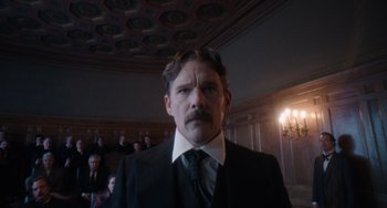 Movie still from “Tesla” (2020), directed by Michael Almereyda – A man in a suit standing in front of a group of people; Close Up shot, Low angle