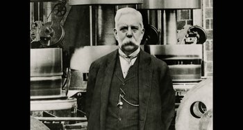 Movie still from “Tesla” (2020), directed by Michael Almereyda – An older man in a suit standing in front of a stove; Close Up shot, Low angle