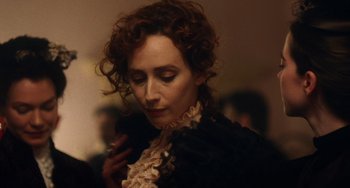 Movie still from “Tesla” (2020), directed by Michael Almereyda – A person with curly hair wearing a dress; Close Up shot, Over the shoulder angle