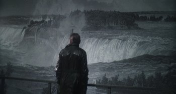 Movie still from “Tesla” (2020), directed by Michael Almereyda – A man standing in front of a waterfall; Wide shot, Over the shoulder angle