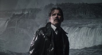 Movie still from “Tesla” (2020), directed by Michael Almereyda – A man in a black jacket standing in front of a waterfall; Close Up shot, Low angle