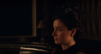 Movie still from “Tesla” (2020), directed by Michael Almereyda – A woman sitting in a dark room looking to her left; Close Up shot, Over the shoulder angle