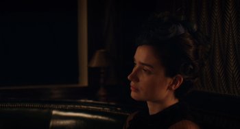 Movie still from “Tesla” (2020), directed by Michael Almereyda – A woman sitting in a dark room looking off into the distance; Close Up shot, Over the shoulder angle