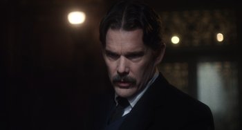 Movie still from “Tesla” (2020), directed by Michael Almereyda – A man with a mustache wearing a suit; Close Up shot, Over the shoulder angle