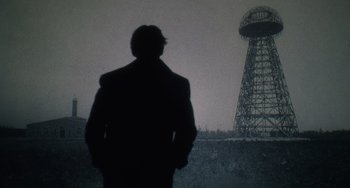 Movie still from “Tesla” (2020), directed by Michael Almereyda – A man standing in front of a large tower; Wide shot, Low angle
