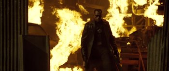 Movie still from “Blade: Trinity” (2004), directed by David S. Goyer – A man with a gun standing in front of a fire; Medium shot, Low angle