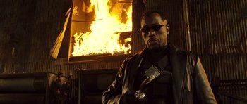 Movie still from “Blade: Trinity” (2004), directed by David S. Goyer – A man holding a wrench in front of a burning building; Close Up shot, Low angle
