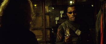 Movie still from “Blade: Trinity” (2004), directed by David S. Goyer – A man holding something in his hand while standing next to a wall; Medium shot, Over the shoulder angle