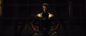 Movie still from “Blade: Trinity” (2004), directed by David S. Goyer – A man sitting on top of a bench in a dark room; Medium shot, Low angle