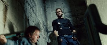 Movie still from “Blade: Trinity” (2004), directed by David S. Goyer – A man standing next to another man smoking a cigarette; Medium shot, Low angle