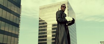 Movie still from “Blade: Trinity” (2004), directed by David S. Goyer – A man in a long black coat standing in front of a tall building; Medium shot, Low angle
