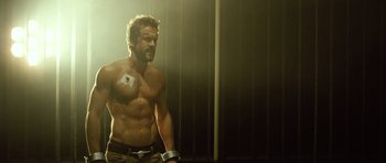 Movie still from “Blade: Trinity” (2004), directed by David S. Goyer – A shirtless man with no shirt is standing in a room; Medium shot, Low angle