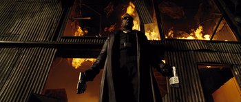Movie still from “Blade: Trinity” (2004), directed by David S. Goyer – A man holding a gun standing in front of a fire; Medium shot, Low angle
