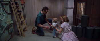 Movie still from “Blast from the Past” (1999), directed by Hugh Wilson – A man kneeling down next to a woman and a baby; Wide shot, High angle