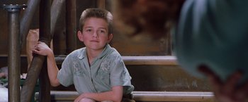 Movie still from “Blast from the Past” (1999), directed by Hugh Wilson – A young boy sitting on steps in front of stairs; Medium shot, Over the shoulder angle