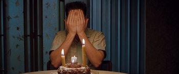Movie still from “Blast from the Past” (1999), directed by Hugh Wilson – A man sitting in front of a birthday cake with lit candles; Medium shot, Overhead angle