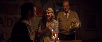 Movie still from “Blast from the Past” (1999), directed by Hugh Wilson – A group of people standing around a table with a lit candle; Medium shot, Over the shoulder angle