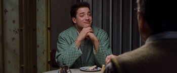 Movie still from “Blast from the Past” (1999), directed by Hugh Wilson – A man sitting at a table with a plate of cake; Medium shot, Over the shoulder angle