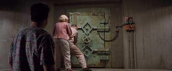 Movie still from “Blast from the Past” (1999), directed by Hugh Wilson – Two people standing in front of a large metal door; Wide shot, High angle