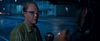 Movie still from “Blast from the Past” (1999), directed by Hugh Wilson – A man with glasses is holding an open umbrella; Close Up shot, Over the shoulder angle