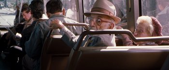 Movie still from “Blast from the Past” (1999), directed by Hugh Wilson – An old man wearing a hat driving a bus; Medium shot, Over the shoulder angle