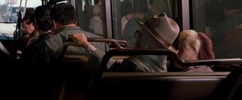 Movie still from “Blast from the Past” (1999), directed by Hugh Wilson – A man sitting on a bus with a hat on his head; Medium shot, Over the shoulder angle