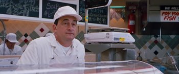 Movie still from “Blast from the Past” (1999), directed by Hugh Wilson – A man sitting in front of a counter in a store; Medium shot, Low angle