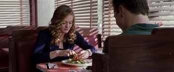 Movie still from “Blast from the Past” (1999), directed by Hugh Wilson – A woman sitting at a table with a plate of food in front of a man; Medium shot, Over the shoulder angle