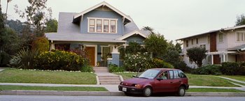 Movie still from “Blast from the Past” (1999), directed by Hugh Wilson – A red car parked in front of a blue house; Wide shot, High angle