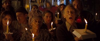 Movie still from “Blast from the Past” (1999), directed by Hugh Wilson – A group of people holding lit candles in front of a crowd; Medium shot, Low angle