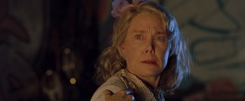 Movie still from “Blast from the Past” (1999), directed by Hugh Wilson – An older woman with blonde curly hair wearing a white shirt and a pink bow; Close Up shot, Low angle