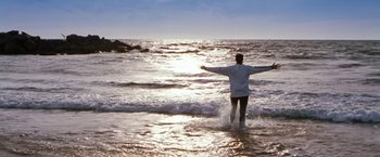 Movie still from “Blast from the Past” (1999), directed by Hugh Wilson – A man standing in the ocean with his arms outstretched; Extreme Wide shot, Low angle