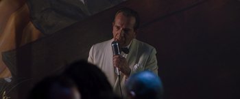 Movie still from “Blast from the Past” (1999), directed by Hugh Wilson – An older man in a white suit is holding a microphone; Medium shot, Low angle