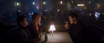 Movie still from “Blast from the Past” (1999), directed by Hugh Wilson – Two people sitting at a table with drinks and a lamp; Medium shot, High angle
