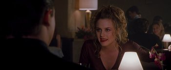 Movie still from “Blast from the Past” (1999), directed by Hugh Wilson – A woman sitting in front of a table with a glass of wine; Close Up shot, Over the shoulder angle