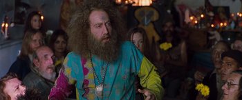 Movie still from “Blast from the Past” (1999), directed by Hugh Wilson – A man with long hair and a long beard is standing in front of a crowd; Medium shot, Over the shoulder angle