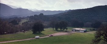 Movie still from “Blast from the Past” (1999), directed by Hugh Wilson – A truck driving down a dirt road near a field; Extreme Wide shot, High angle