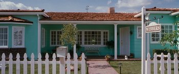 Movie still from “Blast from the Past” (1999), directed by Hugh Wilson – A blue house with a white picket fence and a bench; Extreme Wide shot, High angle