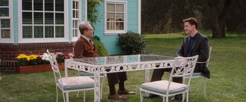 Movie still from “Blast from the Past” (1999), directed by Hugh Wilson – An older man sitting at a table in the grass; Wide shot, Over the shoulder angle