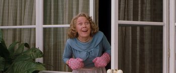 Movie still from “Blast from the Past” (1999), directed by Hugh Wilson – An older woman wearing pink gloves and a blue top; Medium shot, Low angle