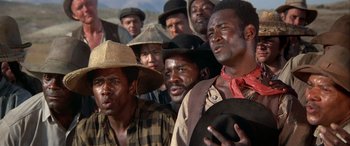 Movie still from “Blazing Saddles” (1974), directed by Mel Brooks – A group of men standing next to each other; Close Up shot, Low angle