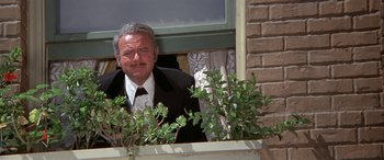 Movie still from “Blazing Saddles” (1974), directed by Mel Brooks – An older man in a suit and tie looking out of a window; Medium shot, Low angle