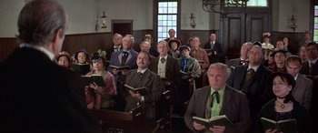 Movie still from “Blazing Saddles” (1974), directed by Mel Brooks – A group of people in suits and ties holding books; Wide shot, High angle