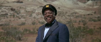 Movie still from “Blazing Saddles” (1974), directed by Mel Brooks – A man in a suit and hat smiling for the camera; Close Up shot, Low angle