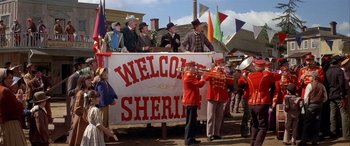 Movie still from “Blazing Saddles” (1974), directed by Mel Brooks – A group of people standing around a sign that says " welcome sheriff "; Wide shot, Low angle