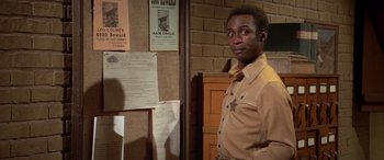 Movie still from “Blazing Saddles” (1974), directed by Mel Brooks – A man standing in front of a bulletin board; Medium shot, Over the shoulder angle