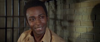 Movie still from “Blazing Saddles” (1974), directed by Mel Brooks – A person smiling for the camera; Close Up shot, Over the shoulder angle