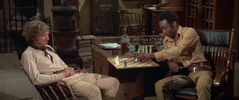 Movie still from “Blazing Saddles” (1974), directed by Mel Brooks – Two men are playing a game of chess in a living room; Medium shot, High angle
