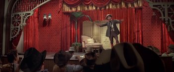 Movie still from “Blazing Saddles” (1974), directed by Mel Brooks – A man standing on a stage in front of a crowd of onlookers; Wide shot, Low angle