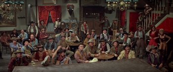 Movie still from “Blazing Saddles” (1974), directed by Mel Brooks – A group of men sitting around a table in a room; Wide shot, High angle